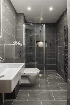 a bathroom with grey tile walls and flooring