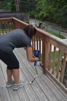 a woman using a power drill on a wooden deck