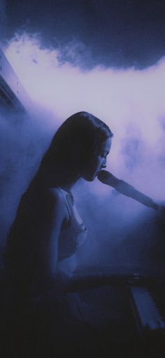 a woman sitting in front of a piano on a cloud filled sky with clouds behind her