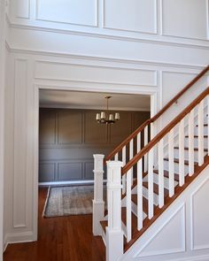 an empty room with white walls and wood floors, stairs leading up to the second floor