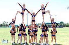 a group of cheerleaders standing on top of each other in the middle of a field