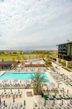 an aerial view of a pool and lounge chairs in the middle of a large open field