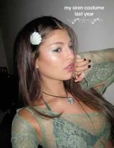 a woman with long brown hair wearing a green dress and white flower in her hair