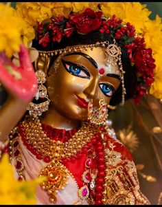 a close up of a statue with flowers on it's head and hands in the air