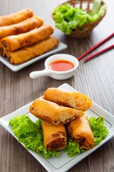 some food is on a white plate with chopsticks and dipping sauce next to it