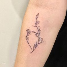 a small flower tattoo on the left arm