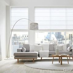 a living room with white furniture and large windows