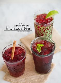 three glasses filled with different types of drinks on top of a cloth covered tablecloth