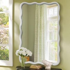 a mirror sitting on top of a dresser next to a window