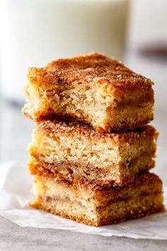 three pieces of cake stacked on top of each other next to a glass of milk