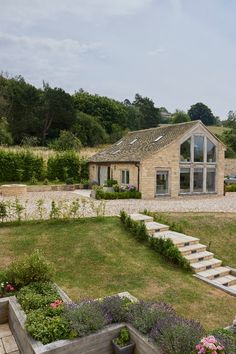 a stone house with steps leading up to it and flowers growing in the front yard