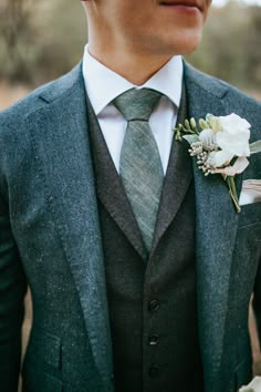 a man wearing a suit and tie with a boutonniere on his lapel