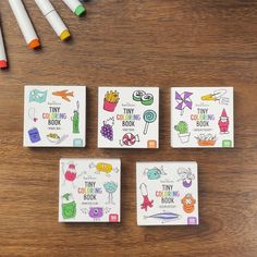 four little books with markers and crayons next to them on a wooden table