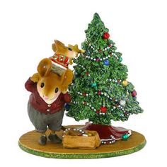 a figurine is standing next to a christmas tree