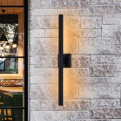 a wall light that is on the side of a building with glass doors and windows