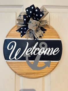 a welcome and anchor sign hanging on the front door with polka dot ribbon attached to it