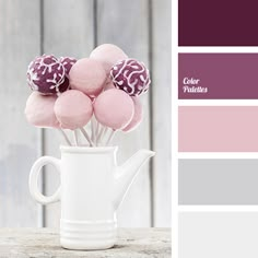 a white vase filled with pink and purple candies on top of a wooden table