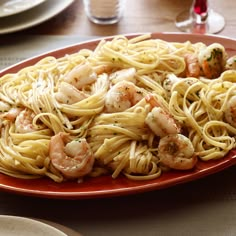 a plate of pasta with shrimp and broccoli on the side at a restaurant