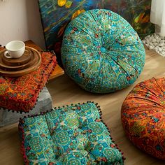 colorful cushions and pillows on the floor in front of a painting