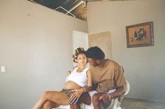 a man sitting next to a woman on top of a white chair in a room