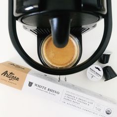 an espresso machine sitting on top of a table next to a tube of coffee