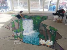 a man sitting on top of a bench next to a painting in the shape of a waterfall