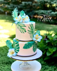 a three tiered cake decorated with tropical leaves and flowers