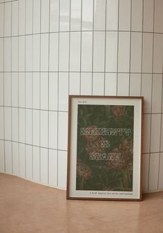 a framed poster sitting on top of a counter next to a wall with white tiles