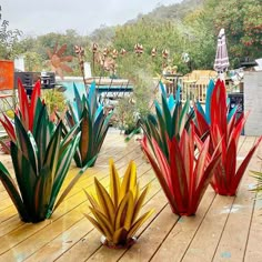 three colorful glass planters sitting on top of a wooden deck next to trees and buildings