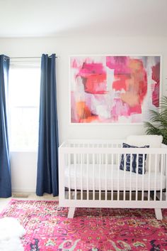 a white crib in front of a window with blue curtains and a pink rug