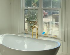 a white bath tub sitting next to two windows