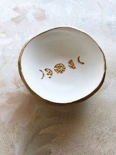 three small gold - plated objects in a white bowl