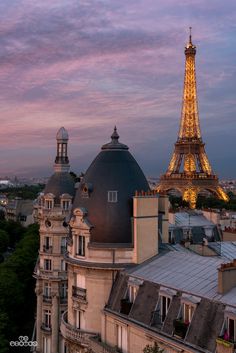 the eiffel tower is lit up at night, with other buildings in the background