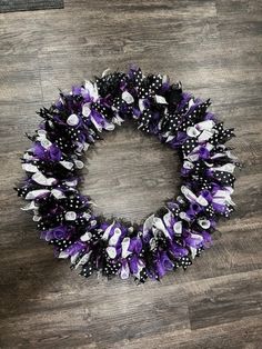 a purple and black wreath with white polka dots on the bottom, sitting on a wooden floor