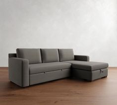 a gray couch sitting on top of a hard wood floor next to a white wall