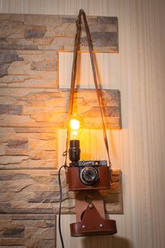 an old fashioned camera hanging on a wall with a light attached to the back of it