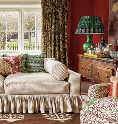 a living room filled with furniture and a green lamp on top of a table in front of a window