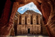 an arch in the side of a rock formation with a building on it's sides