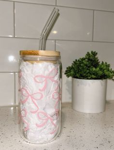 a glass jar filled with shredded white paper and a straw sticking out of the lid