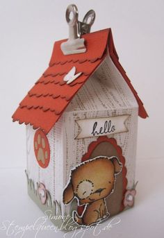 a small house with a dog on the roof and a name tag attached to it