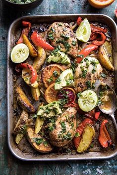 chicken and veggies in a roasting pan with lemons, tomatoes, zucchini, and parsley