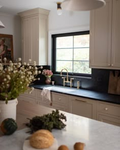 a kitchen with white cabinets and black counter tops, along with flowers in a vase