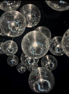 many glass balls are hanging from the ceiling in black and white photo, with light shining on them