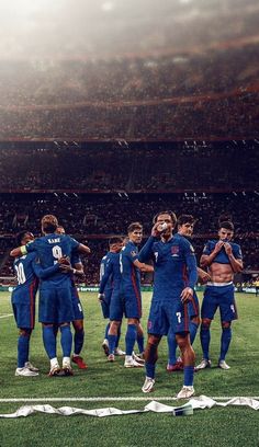 a group of soccer players huddle together on the field in front of an empty stadium