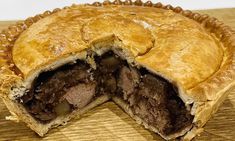 a meat pie cut in half on top of a wooden cutting board