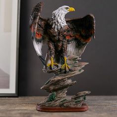 an eagle figurine sitting on top of a piece of driftwood next to a framed photograph