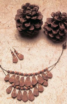 a necklace and earrings with pine cones on the ground