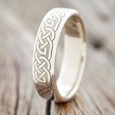 a wedding ring with an intricate design on the inside is sitting on a wooden surface