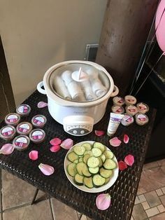 a table topped with cucumbers and cupcakes next to a crock pot