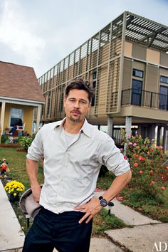 a man standing in front of a house with his hands on his hips and looking at the camera